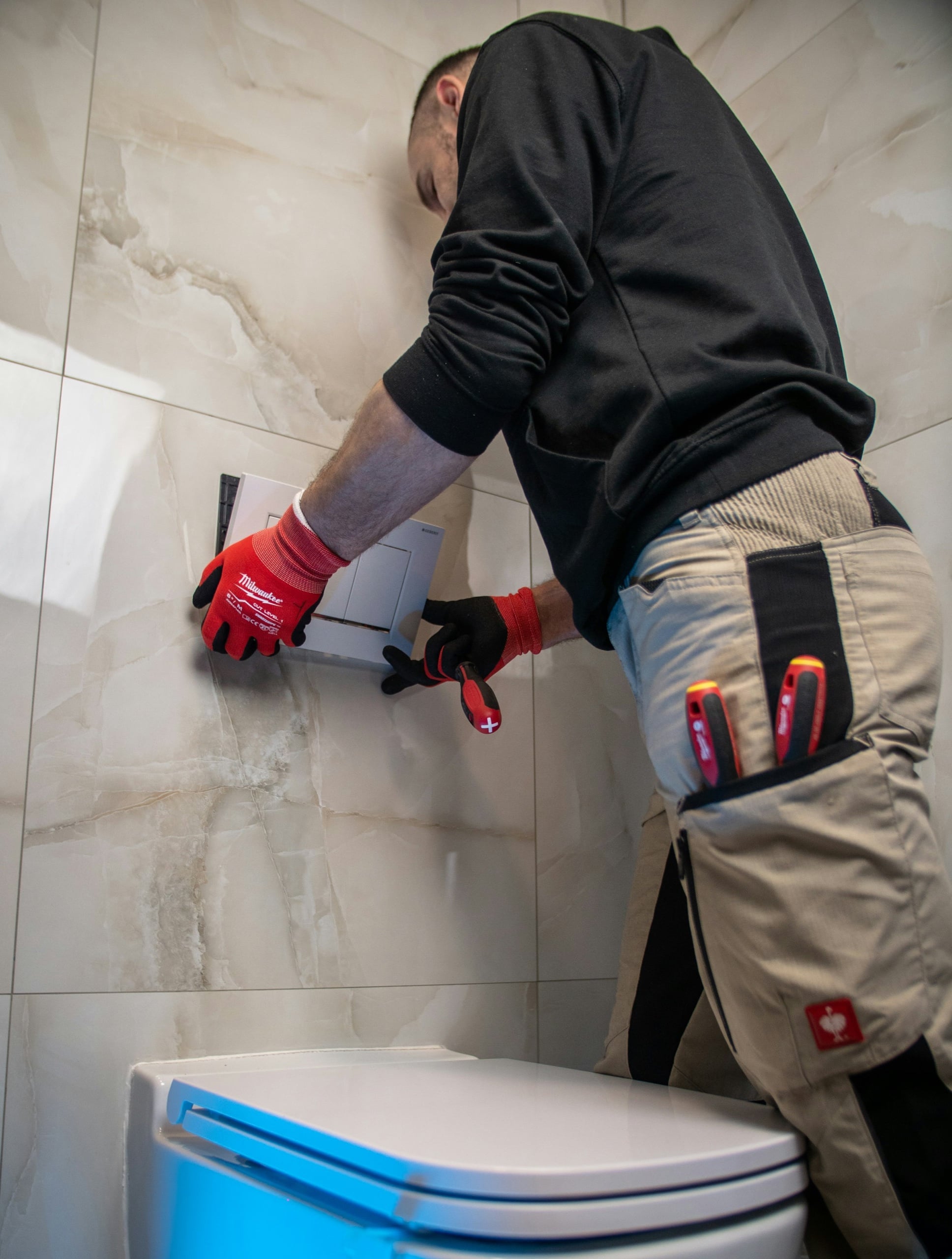 Plumber fitting a concealed cistern flush plate in a renovated bathroom