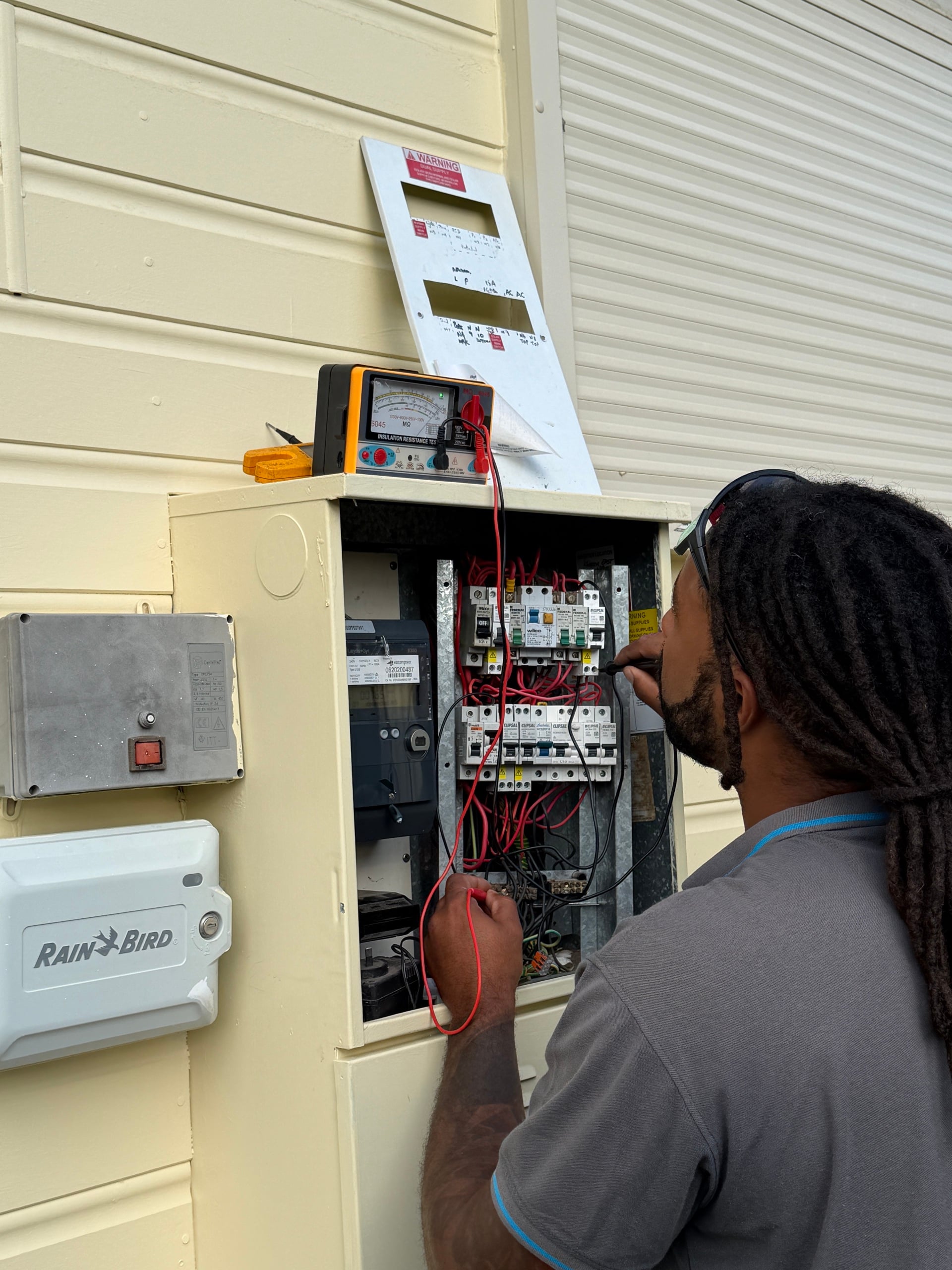 Riverside electrician testing switchboard wiring with a multimeter on an emergency call-out in Perth