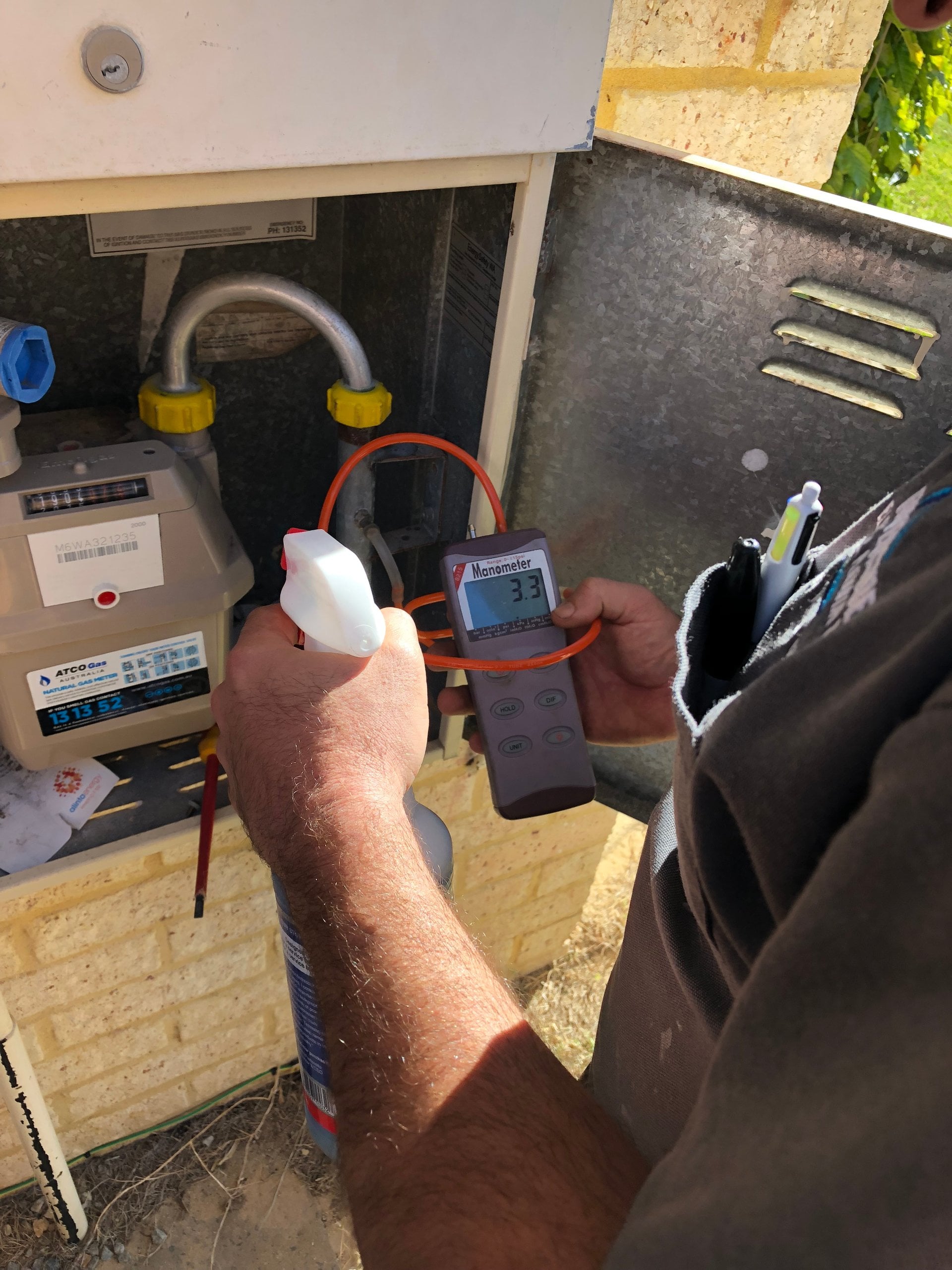Riverside gas fitter pressure-testing a gas meter with a manometer to find a leak