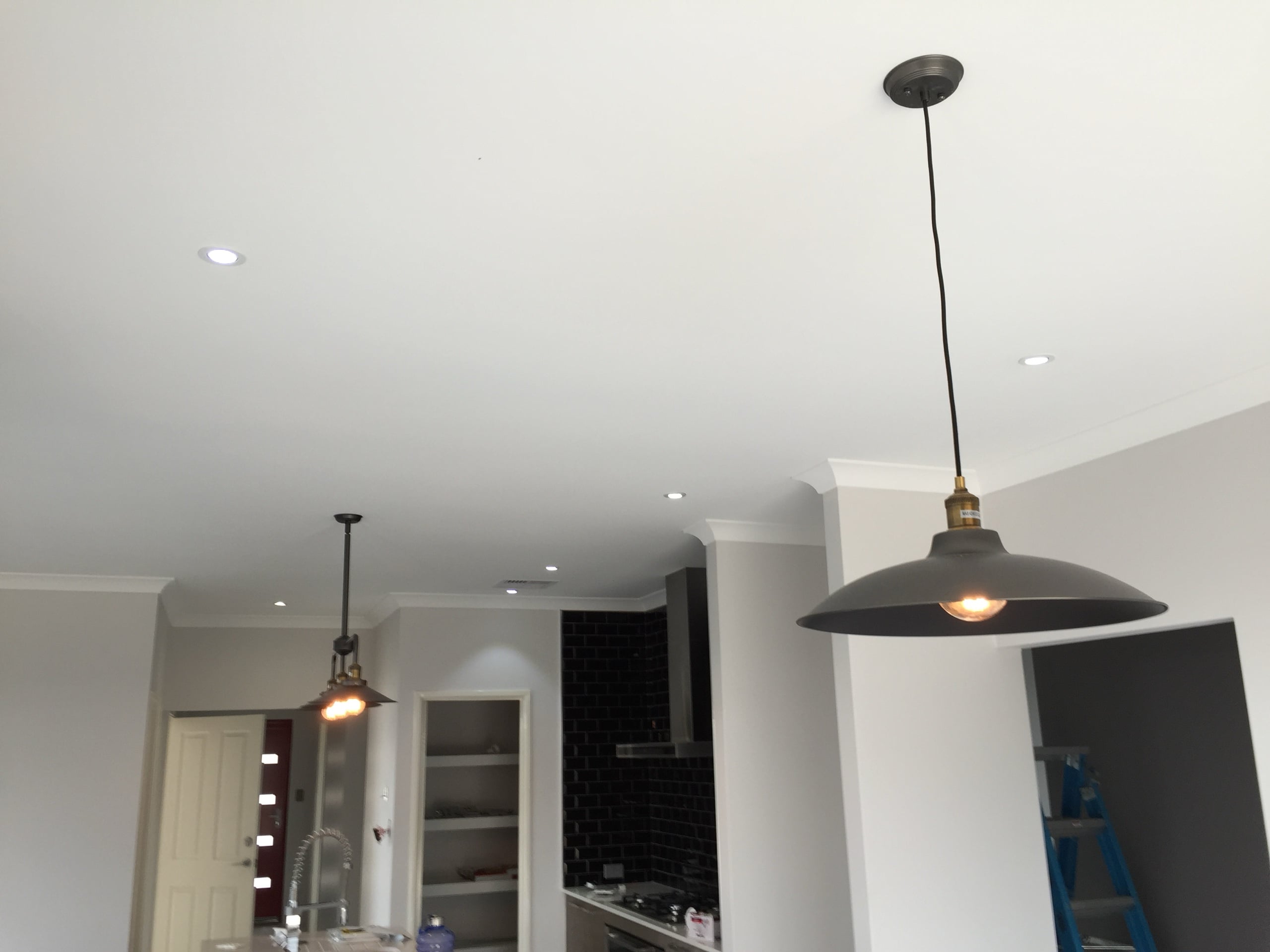 LED downlights and pendant lights installed across an open-plan kitchen and living area