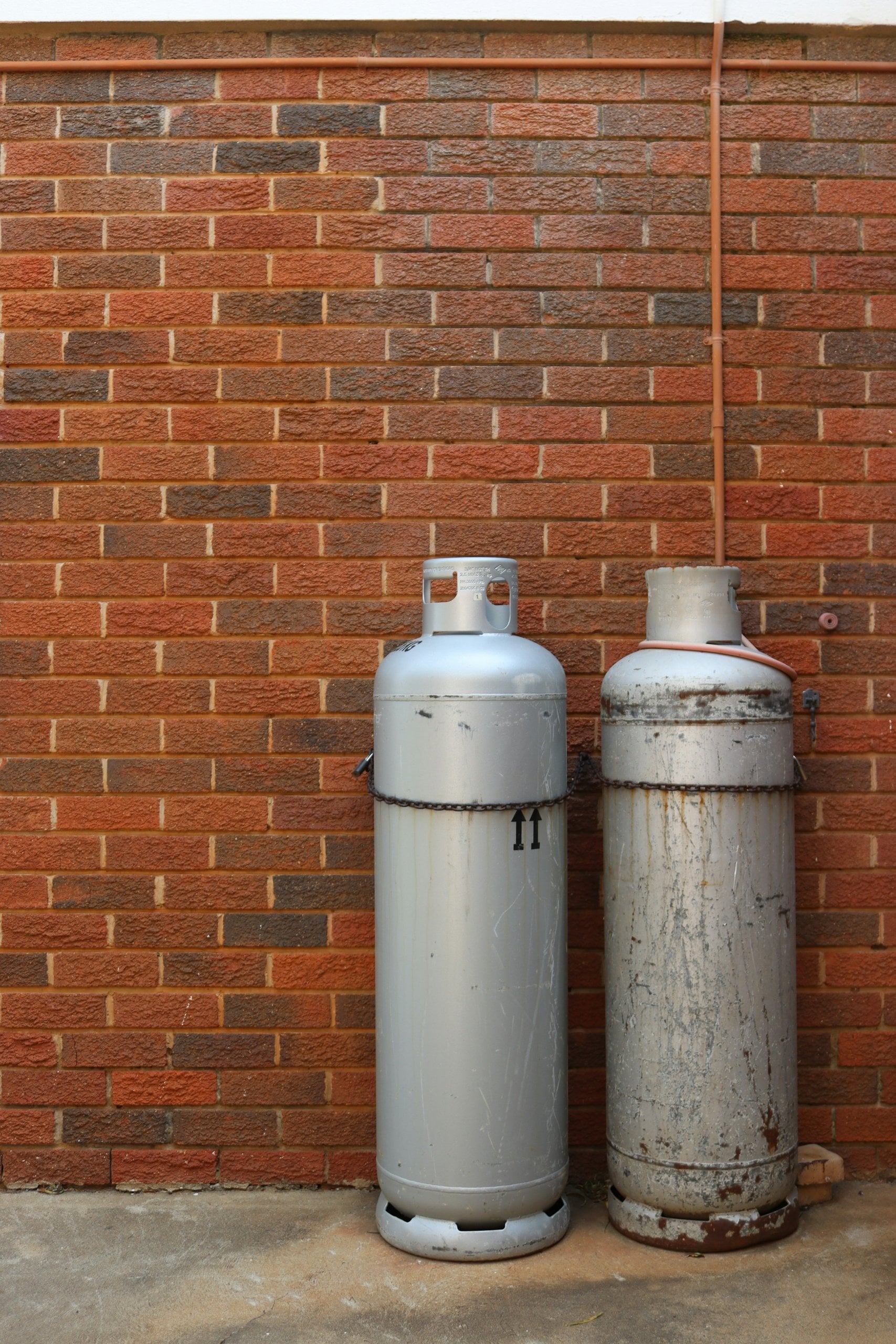 LPG gas bottles connected against a brick wall at a Perth home