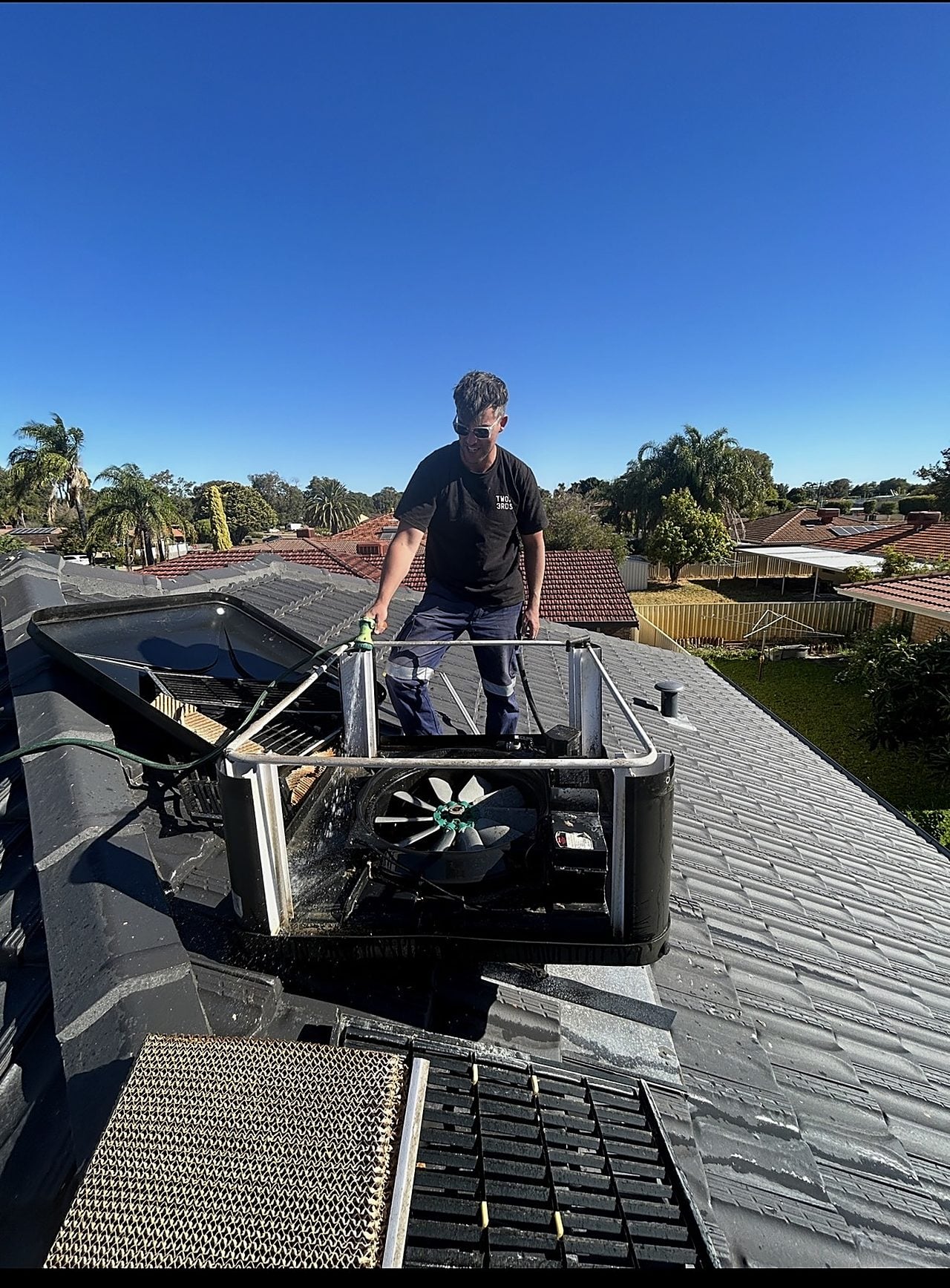 A Riverside technician servicing a ducted air conditioning unit on a Perth roof