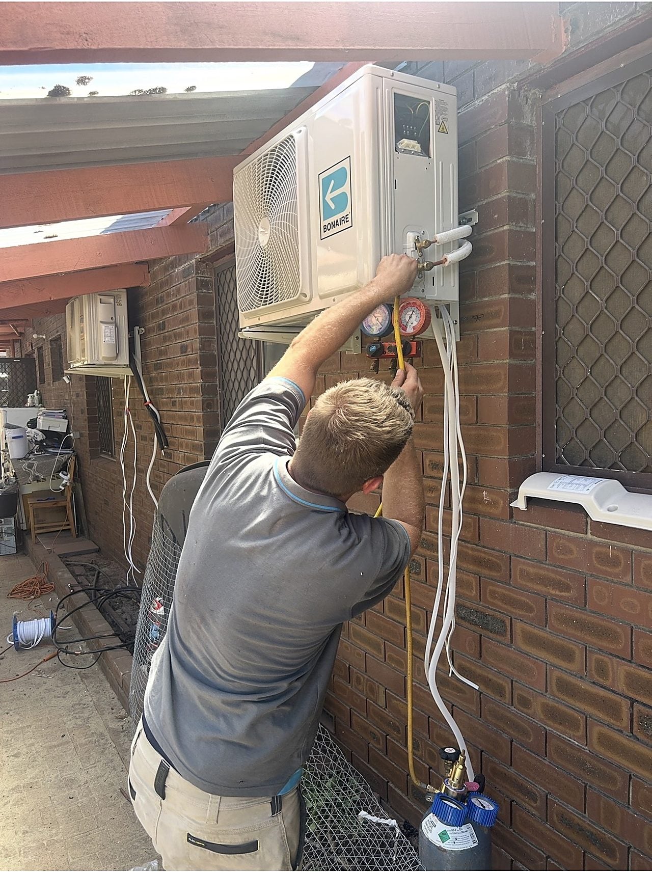 A Riverside technician connecting a split system outdoor unit at a Perth home