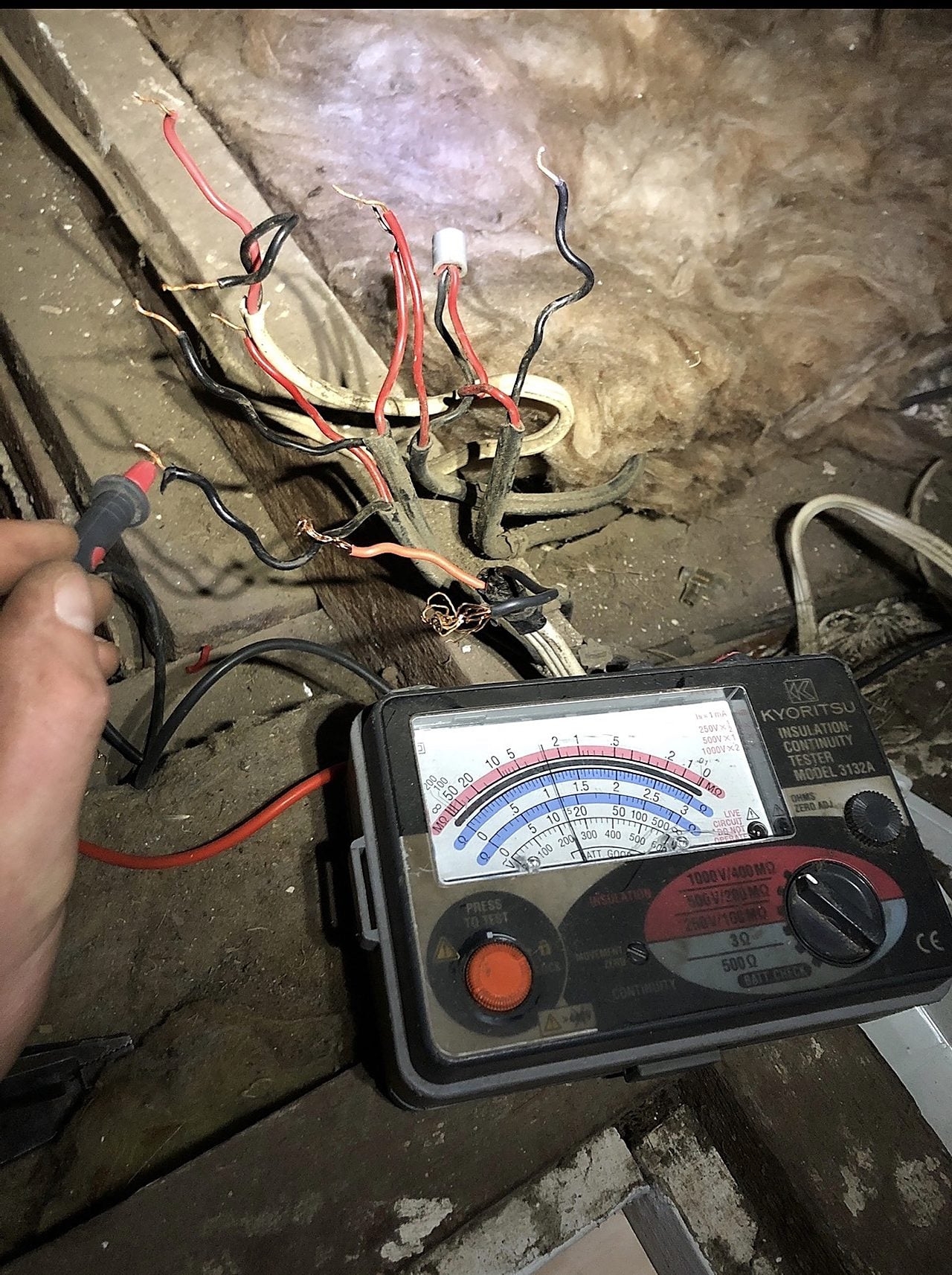 Old wiring being tested in a roof cavity during a house rewire
