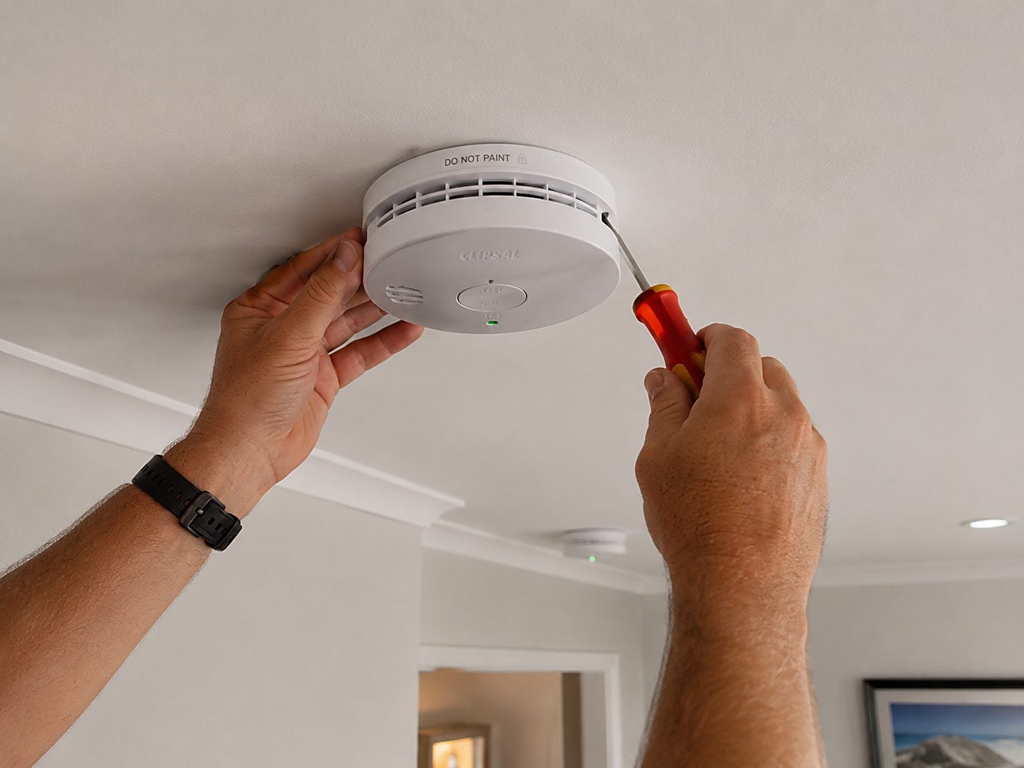 A photoelectric smoke alarm being fitted to a ceiling