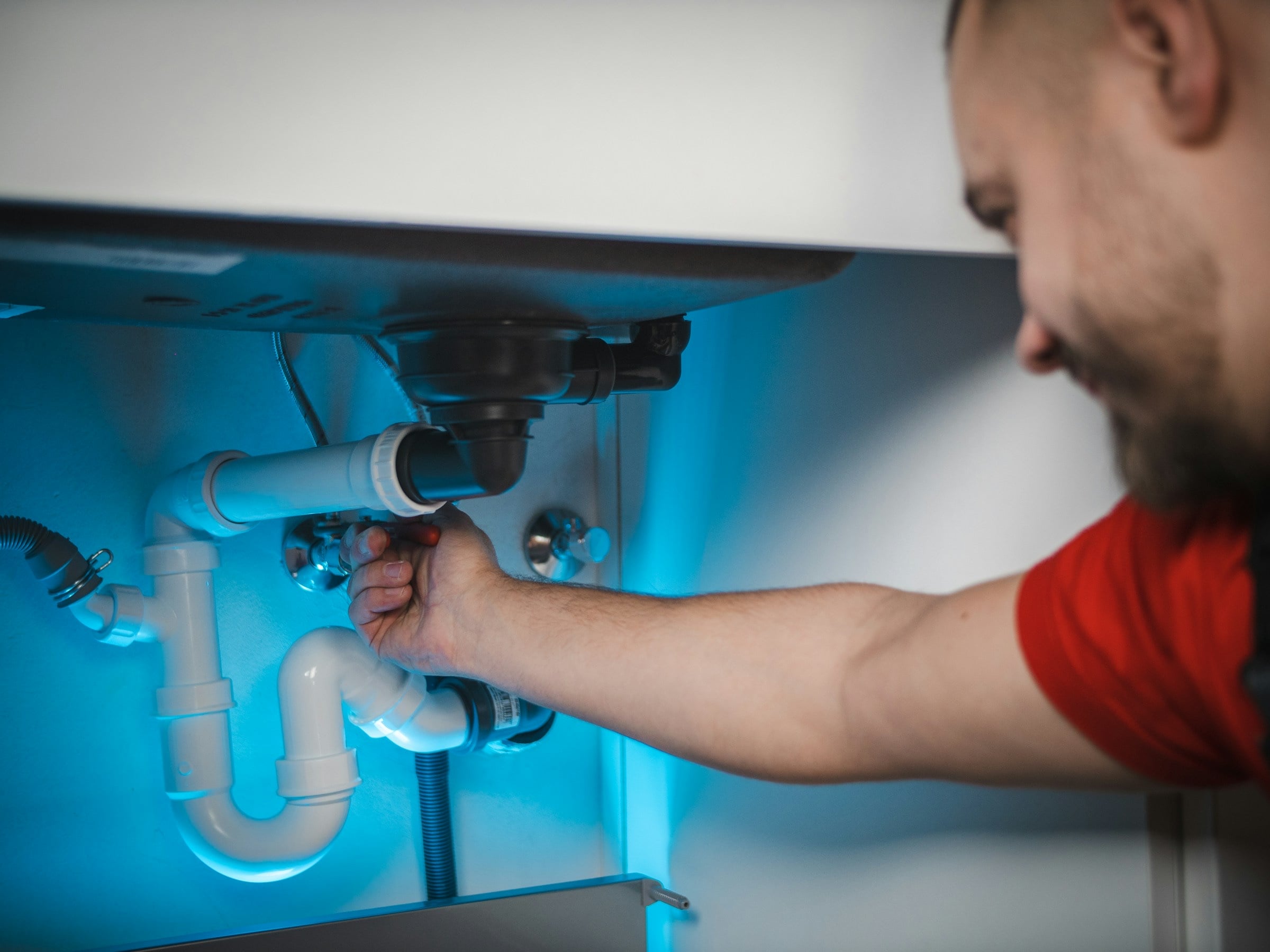 Riverside plumber working on the pipework under a kitchen sink at a Perth home